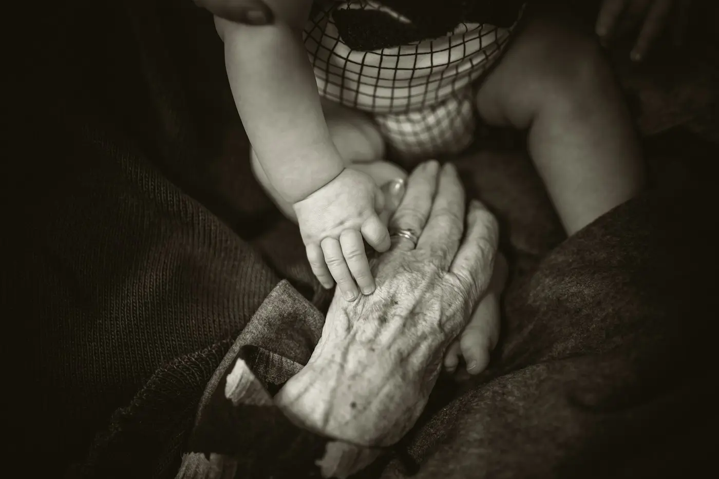 Mano de una mujer mayor sosteniendo la mano de un bebé